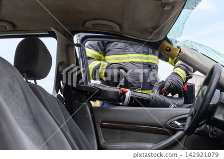 Firefighter Using Hydraulic Rescue Tool To Extricate Occupant From Crashed Car At Accident Scene Firefighter Using Hydraulic Rescue Tool To Extricate Occupant From Crashed Car At Accident Scene 142921079