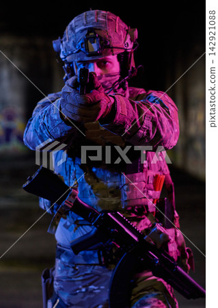 Soldier Aiming Pistol In Tactical Gear With Rifle At Night Under Neon Lighting Soldier Aiming Pistol In Tactical Gear With Rifle At Night Under Neon Lighting 142921088