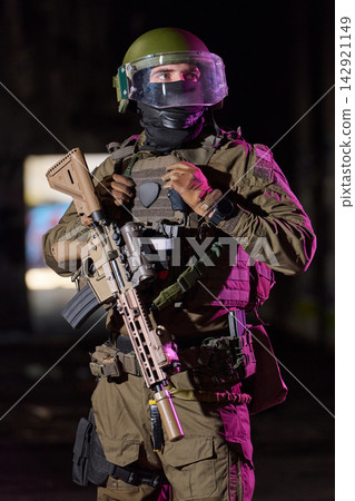 Armed Tactical Soldier In Ballistic Helmet And Body Armor Holding Assault Rifle On Night Patrol Armed Tactical Soldier In Ballistic Helmet And Body Armor Holding Assault Rifle On Night Patrol 142921149