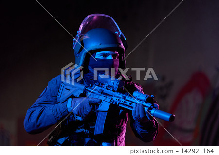 Armed SWAT Officer in Tactical Gear Holding Rifle During Night Operation With Blue and Purple Lighting Armed SWAT Officer in Tactical Gear Holding Rifle During Night Operation With Blue and Purple Lighting 142921164