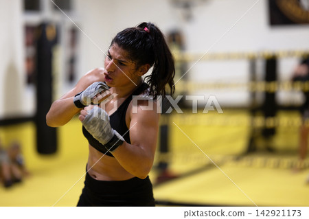 Female Boxer Training in Boxing Gym Practicing Punches and Conditioning During Intense Workout Female Boxer Training in Boxing Gym Practicing Punches and Conditioning During Intense Workout 142921173