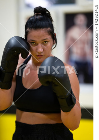 Determined Female Boxer Training in Gym With Gloves Practicing Intense Fitness Workout Determined Female Boxer Training in Gym With Gloves Practicing Intense Fitness Workout 142921419