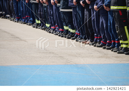 Row Of Firefighters Standing in Uniform Line Formation During Ceremony Showing Teamwork And Discipline Row Of Firefighters Standing in Uniform Line Formation During Ceremony Showing Teamwork And Discipline 142921421