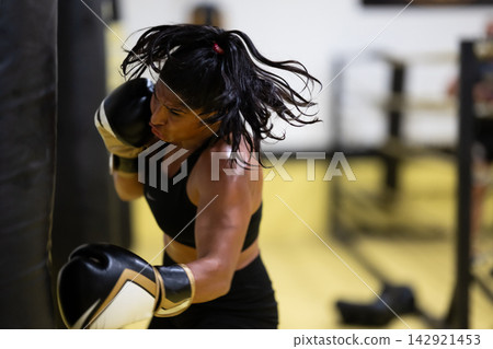 Female Boxer Training With Punching Bag in Gym Showing Strength, Power and Determination During Workout Female Boxer Training With Punching Bag in Gym Showing Strength, Power and Determination During Workout 142921453