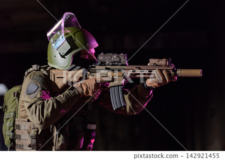 Soldier Aiming Tactical Rifle With Ballistic Helmet, Optic Scope and Suppressor During Low-Light Operation 142921455