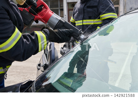 Firefighters Using Saw To Cut Windshield During Car Rescue And Extrication Operation Firefighters Using Saw To Cut Windshield During Car Rescue And Extrication Operation 142921588