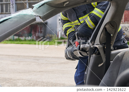 Firefighter Using Hydraulic Rescue Tool To Extricate Passenger From Crashed Car During Emergency Response Firefighter Using Hydraulic Rescue Tool To Extricate Passenger From Crashed Car During Emergency Response 142921622