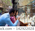 Couple window shopping at a jewelry store admiring rings and necklaces in a glass display 142922028