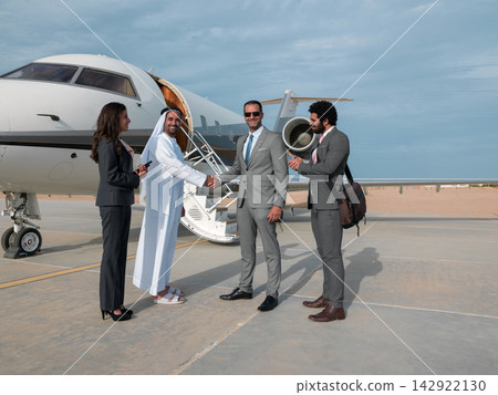 Middle Eastern business team greeting partners at a private jet on a desert tarmac after a deal Middle Eastern business team greeting partners at a private jet on a desert tarmac after a deal 142922130