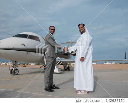 Middle Eastern businessmen shaking hands by private jet on tarmac after successful business deal Middle Eastern businessmen shaking hands by private jet on tarmac after successful business deal 142922151
