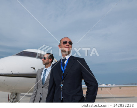Middle Eastern business team standing confidently by their private jet at a sunny airport tarmac Middle Eastern business team standing confidently by their private jet at a sunny airport tarmac 142922238