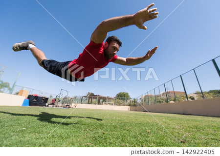 Athlete diving forward during outdoor CrossFit workout at an open-air fitness gym with friend Athlete diving forward during outdoor CrossFit workout at an open-air fitness gym with friend 142922405