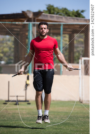 Middle Eastern Arab man jump roping outdoors at open-air fitness gym during CrossFit workout Middle Eastern Arab man jump roping outdoors at open-air fitness gym during CrossFit workout 142922407