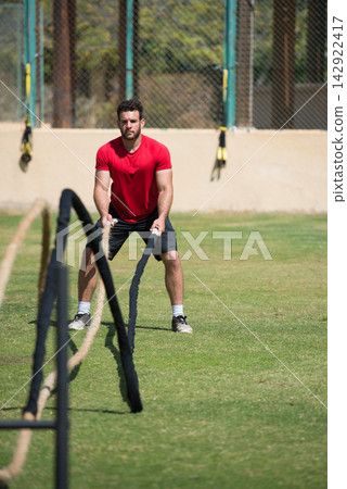 Middle Eastern man training outdoors with battle ropes in a CrossFit style fitness workout Middle Eastern man training outdoors with battle ropes in a CrossFit style fitness workout 142922417