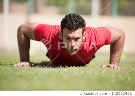 Middle Eastern man doing outdoor pushups in a CrossFit style workout preparing with a friend Middle Eastern man doing outdoor pushups in a CrossFit style workout preparing with a friend 142922436
