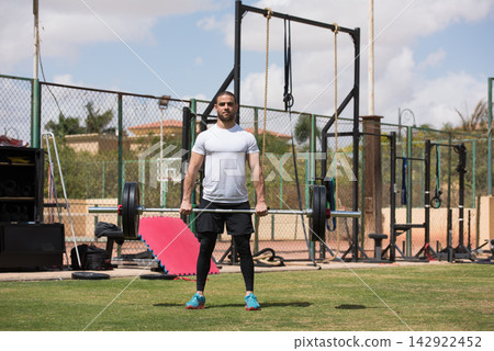 Middle Eastern man performing deadlift at outdoor crossfit gym for strength and fitness training Middle Eastern man performing deadlift at outdoor crossfit gym for strength and fitness training 142922452