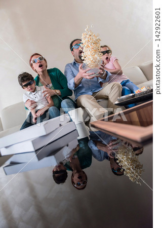 Modern Middle Eastern family watching movie together at home with popcorn flying in living room surprise Modern Middle Eastern family watching movie together at home with popcorn flying in living room surprise 142922601