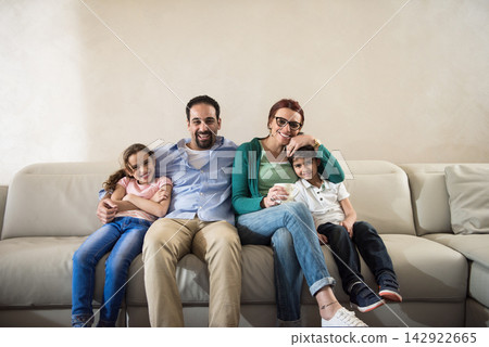 Modern Middle Eastern family of four smiling together on a living room couch with parents and kids Modern Middle Eastern family of four smiling together on a living room couch with parents and kids 142922665