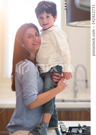 Middle Eastern mother holding son in kitchen celebrating Eid and Ramadan iftar at modern home 142922731
