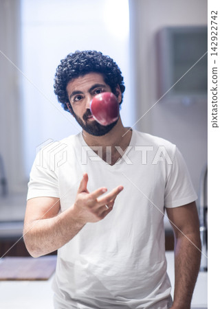 Middle Eastern man tossing an apple in a modern kitchen during Ramadan iftar at home Middle Eastern man tossing an apple in a modern kitchen during Ramadan iftar at home 142922742