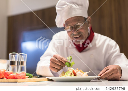 Elderly chef preparing iftar salad for a modern Middle Eastern family during Ramadan celebration at home Elderly chef preparing iftar salad for a modern Middle Eastern family during Ramadan celebration at home 142922796
