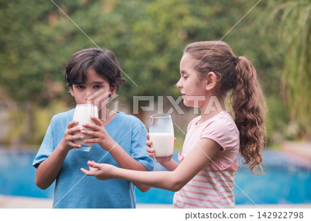 Middle Eastern modern family sharing milk outdoors during Ramadan iftar with children in backyard pool setting Middle Eastern modern family sharing milk outdoors during Ramadan iftar with children in backyard pool setting 142922798