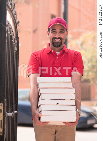 Smiling pizza delivery man bringing multiple boxes to a Middle Eastern family for Ramadan iftar celebration Smiling pizza delivery man bringing multiple boxes to a Middle Eastern family for Ramadan iftar celebration 142922817