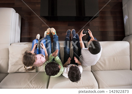 Modern Middle Eastern family kids playing video games together on couch during Eid Ramadan at home Modern Middle Eastern family kids playing video games together on couch during Eid Ramadan at home 142922873