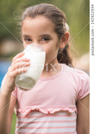Middle Eastern girl drinking a glass of milk during Ramadan iftar at modern family home Middle Eastern girl drinking a glass of milk during Ramadan iftar at modern family home 142922934