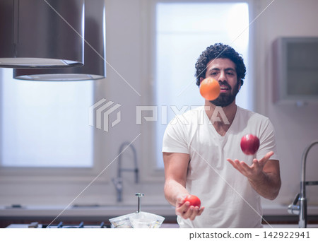 Middle Eastern man juggling fruit in modern kitchen during Ramadan iftar family dinner celebration Middle Eastern man juggling fruit in modern kitchen during Ramadan iftar family dinner celebration 142922941