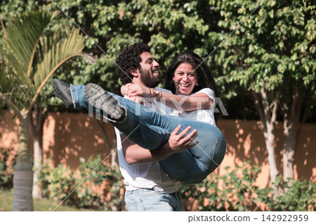 Middle Eastern couple celebrating Eid and Ramadan iftar with joyful embrace in modern home garden Middle Eastern couple celebrating Eid and Ramadan iftar with joyful embrace in modern home garden 142922959