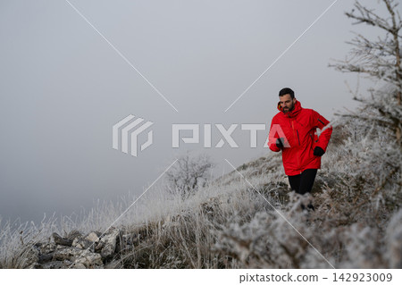 Man Running On Frosty Mountain Trail In Red Jacket During Winter Outdoor Fitness Training Man Running On Frosty Mountain Trail In Red Jacket During Winter Outdoor Fitness Training 142923009