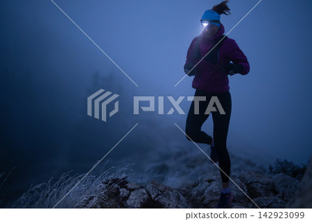 Trail Runner With Headlamp Running On Rocky Ridge At Night In Foggy Cold Conditions Trail Runner With Headlamp Running On Rocky Ridge At Night In Foggy Cold Conditions 142923099