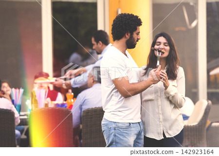 Middle Eastern couple sharing food at a family backyard barbecue with friends and relaxed atmosphere 142923164