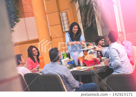 Middle Eastern modern Arab family enjoying outdoor meal together with friends and children at a festive gathering Middle Eastern modern Arab family enjoying outdoor meal together with friends and children at a festive gathering 142923171
