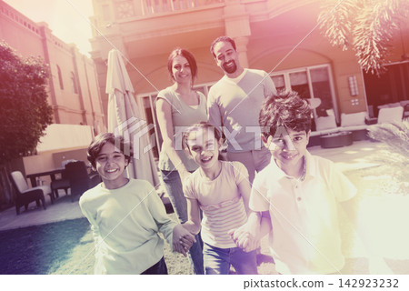 Middle Eastern modern family enjoying playful backyard lifestyle with parents and smiling children 142923232