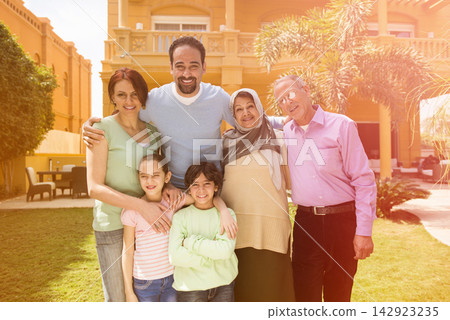 Middle Eastern modern Arab family enjoying multigenerational outdoor time at home in sunny courtyard Middle Eastern modern Arab family enjoying multigenerational outdoor time at home in sunny courtyard 142923235