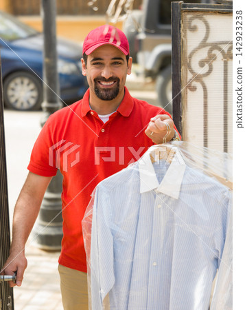 Middle Eastern Arab multigeneration family receives dry cleaning delivery at modern luxury villa from smiling courier Middle Eastern Arab multigeneration family receives dry cleaning delivery at modern luxury villa from smiling courier 142923238