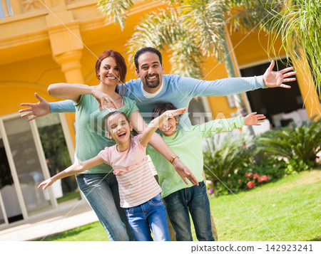 Multigenerational family enjoying time together in front of modern luxury villa, smiling and playful 142923241