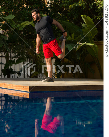 Man stretching before workout on villa pool deck in a luxury backyard fitness session 142923270