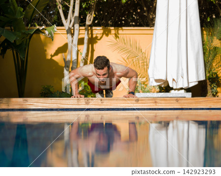 Man doing push-ups by a luxury villa pool during a family stay at a modern multigenerational home Man doing push-ups by a luxury villa pool during a family stay at a modern multigenerational home 142923293