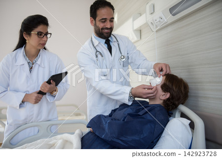 Doctors apply eye patch to patient in modern Egyptian eye hospital clinic during postoperative care 142923728