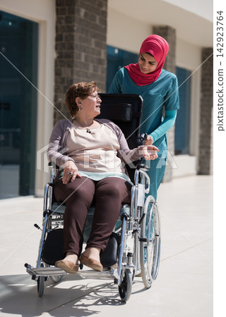 Middle Eastern nurse assisting elderly patient in wheelchair at modern eye hospital clinic in Egypt 142923764