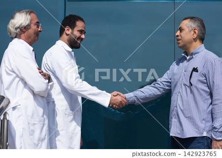 Doctors and patient shaking hands outside a modern Middle Eastern eye hospital clinic in Egypt Doctors and patient shaking hands outside a modern Middle Eastern eye hospital clinic in Egypt 142923765