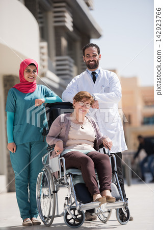 Eye hospital team caring for smiling elderly patient in wheelchair at modern Middle Eastern clinic in Egypt 142923766