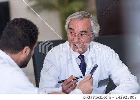 Senior Middle Eastern eye surgeon consulting with colleague in modern Egypt clinic meeting Senior Middle Eastern eye surgeon consulting with colleague in modern Egypt clinic meeting 142923802