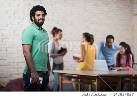 Middle Eastern startup team collaborating in a creative coworking space with smiling young businesspeople Middle Eastern startup team collaborating in a creative coworking space with smiling young businesspeople 142924027