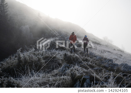 Couple Hiking on Frosty Mountain Trail in Foggy Morning Light Couple Hiking on Frosty Mountain Trail in Foggy Morning Light 142924105