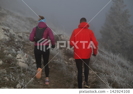 Couple Trail Running Through Foggy Frosty Mountain Path During Winter Outdoor Workout Couple Trail Running Through Foggy Frosty Mountain Path During Winter Outdoor Workout 142924108