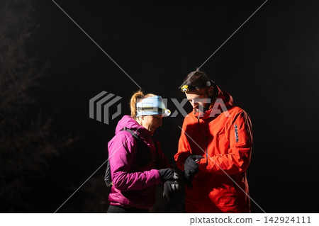 Couple Night Hikers Checking Gear With Headlamps During Cold Outdoor Winter Adventure In Wilderness Couple Night Hikers Checking Gear With Headlamps During Cold Outdoor Winter Adventure In Wilderness 142924111